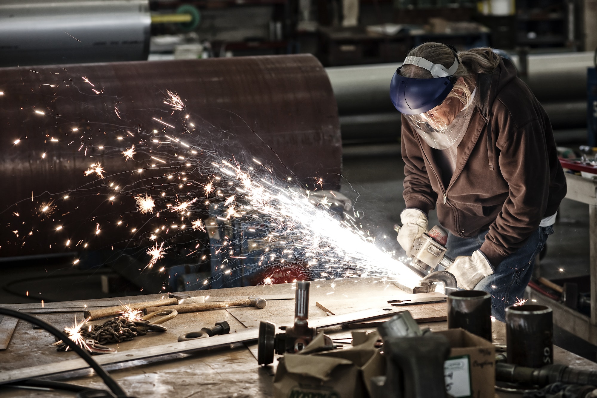 Factory worker grinding a steel edge in a sheet metal factory.